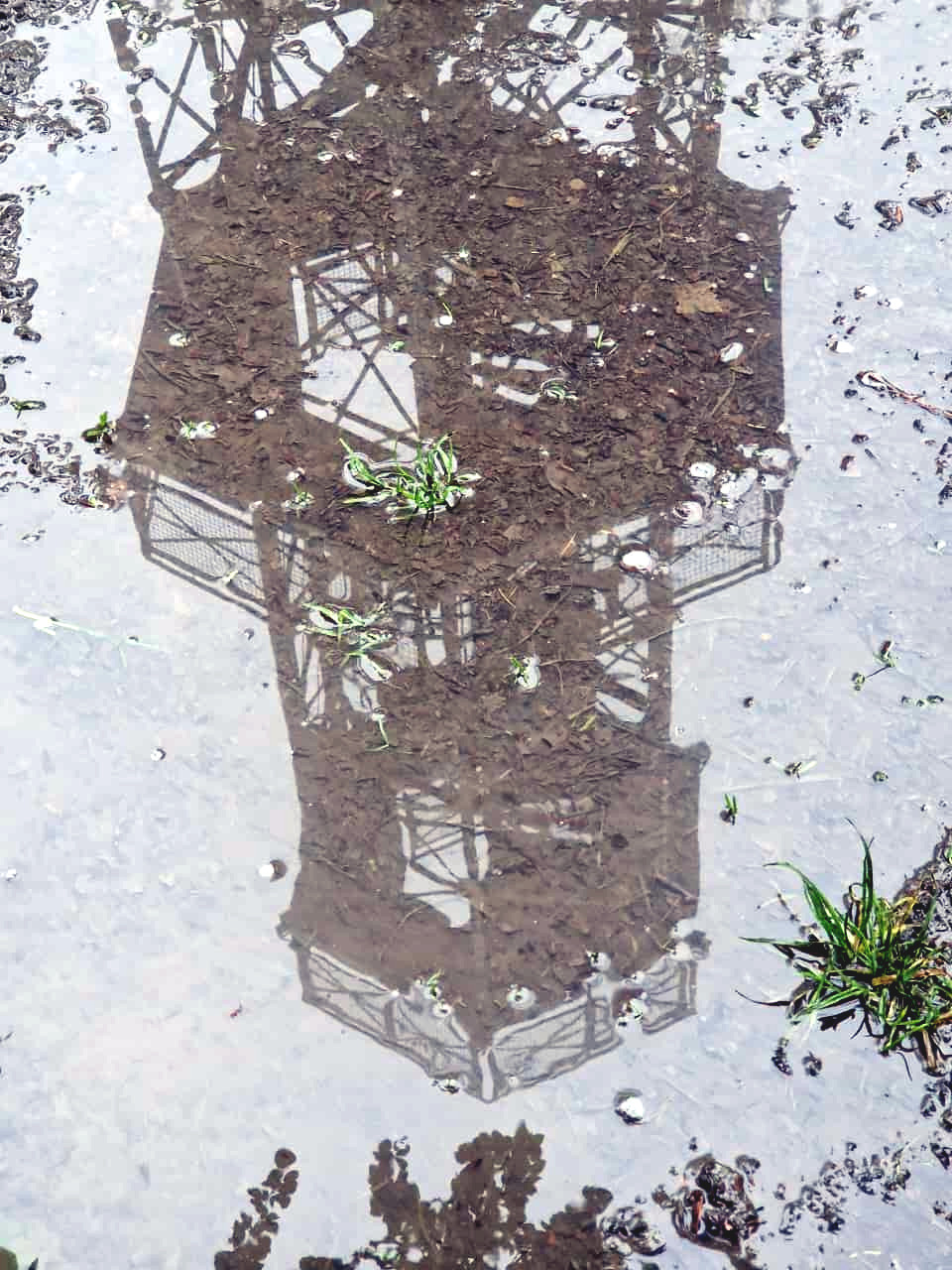 Perfect reflection of the tower in a puddle.